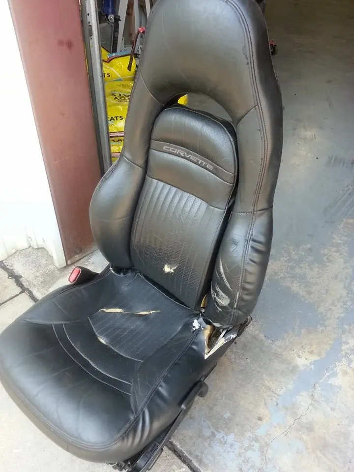 Damaged black vinyl vehicle seat before repair