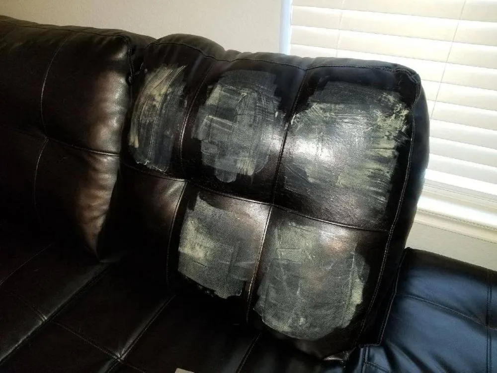 Black leather cushion with burn and hole damage before repair