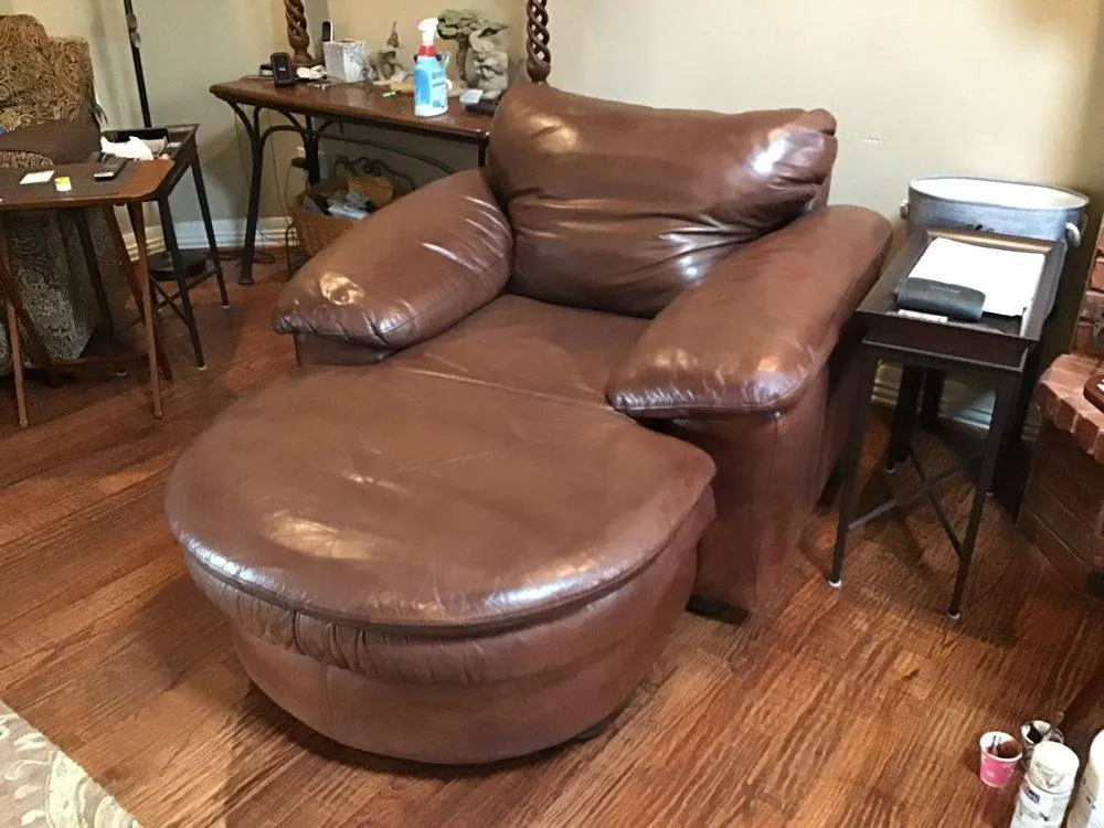 Worn leather chair and ottoman awaiting furniture repair