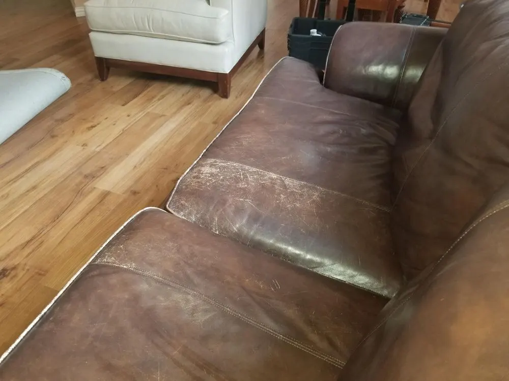 Worn leather chaise with a stiff, dulled surface across the seat