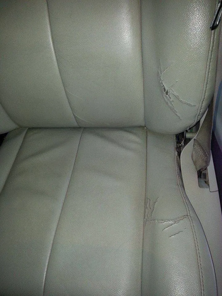 Gray leather seat showing surface cracking before repair